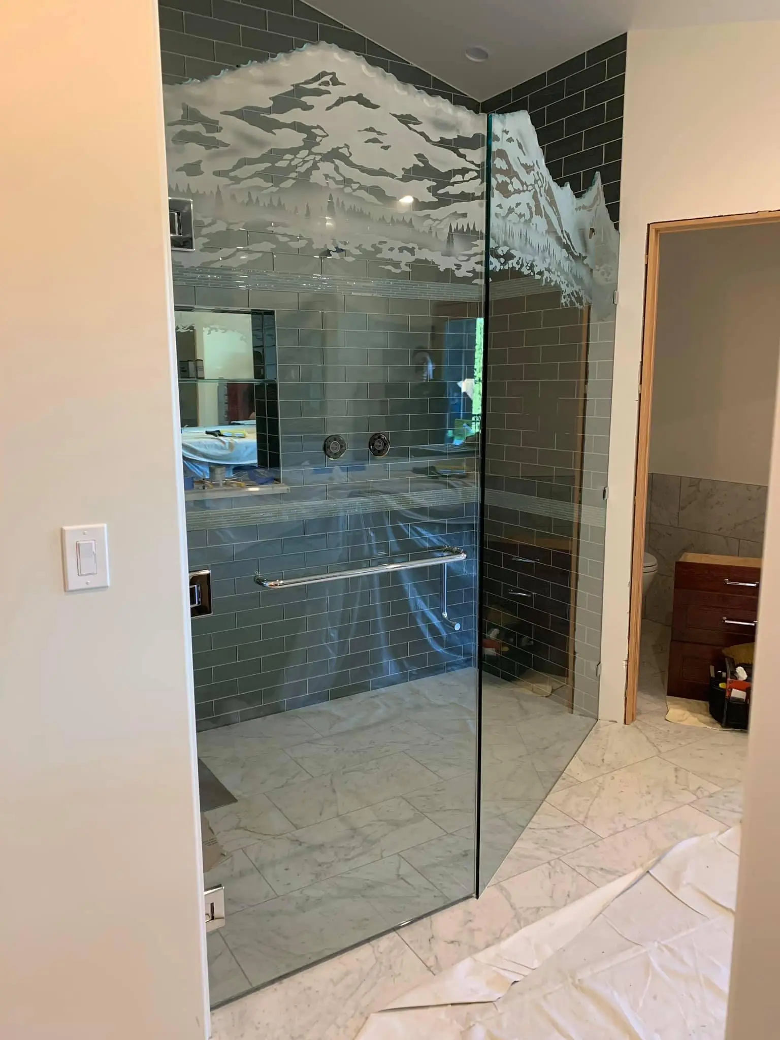 Shower enclosure etched with a mountain and valley scene.